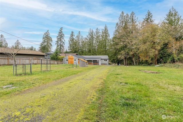 view of yard featuring a garage, fence, and driveway