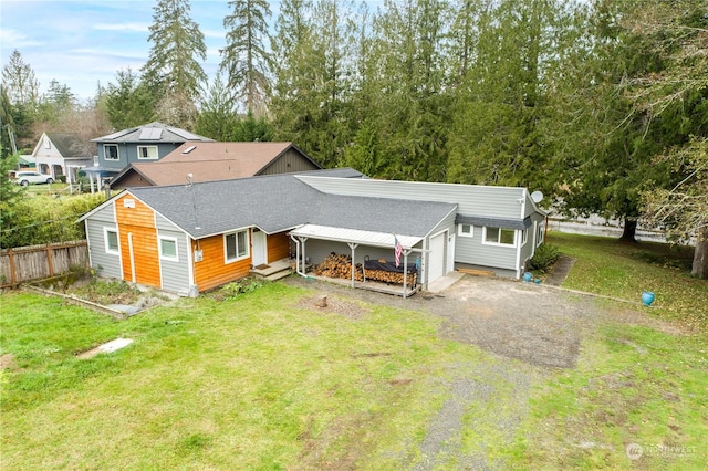 back of house with driveway, a shingled roof, a lawn, and fence