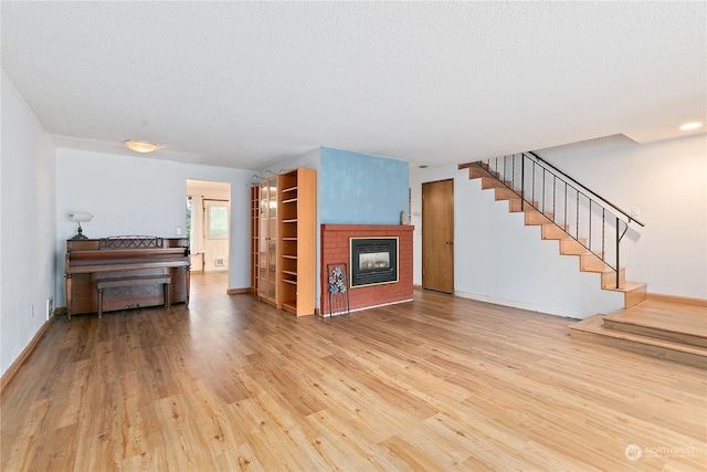 unfurnished living room featuring a fireplace, wood-type flooring, and a textured ceiling