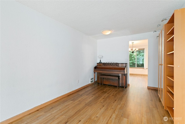 miscellaneous room featuring hardwood / wood-style floors, a textured ceiling, and a chandelier