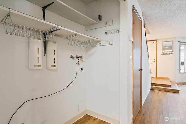 laundry room featuring a textured ceiling and hardwood / wood-style flooring