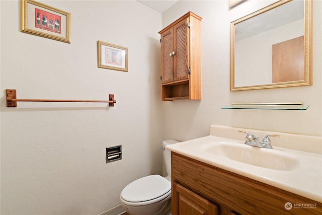 bathroom with vanity, toilet, and a textured ceiling