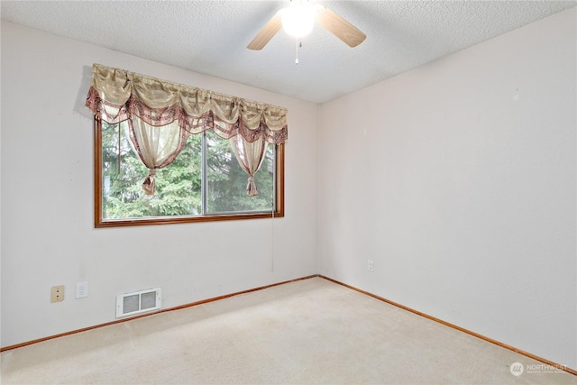 carpeted spare room with ceiling fan and a textured ceiling