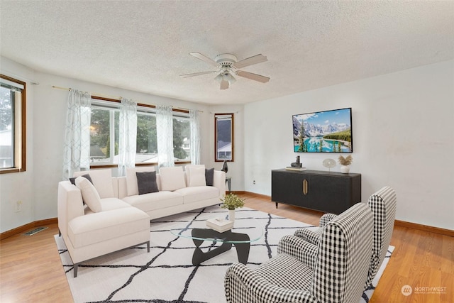 living room featuring a textured ceiling, light hardwood / wood-style flooring, and ceiling fan