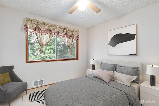 bedroom with ceiling fan and a textured ceiling