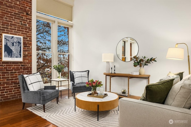 sitting room featuring wood-type flooring and brick wall