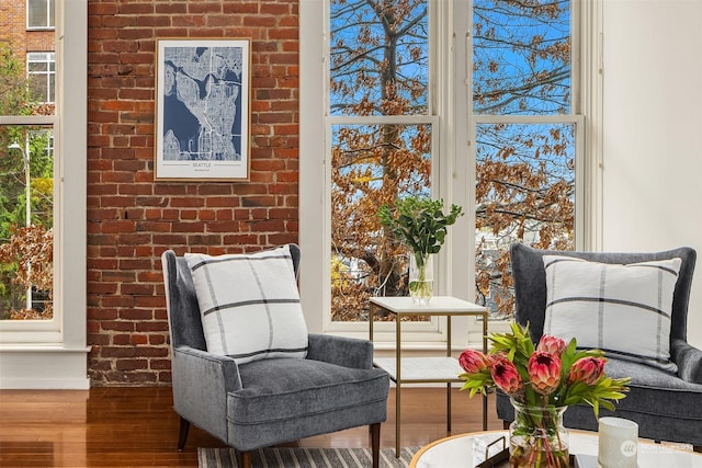 living area with hardwood / wood-style floors and brick wall