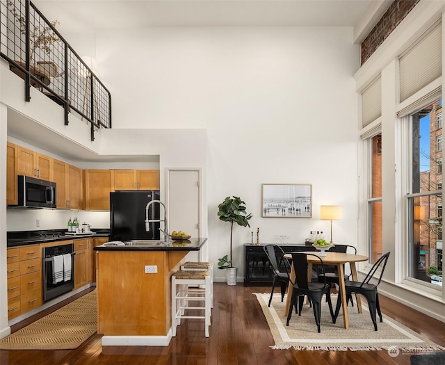 kitchen featuring a kitchen island with sink, a kitchen breakfast bar, sink, dark hardwood / wood-style flooring, and stainless steel appliances