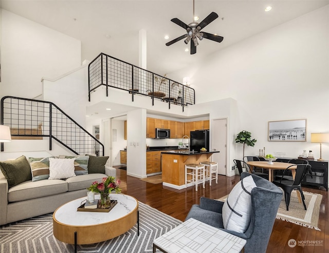 living room with ceiling fan, dark hardwood / wood-style flooring, sink, and a high ceiling