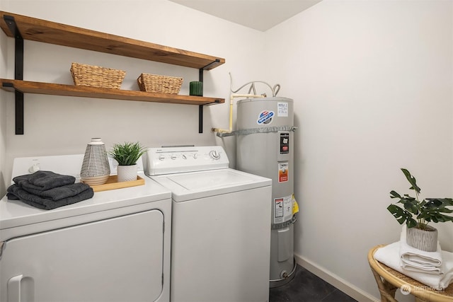 laundry room with washer and dryer, strapped water heater, and dark tile patterned flooring