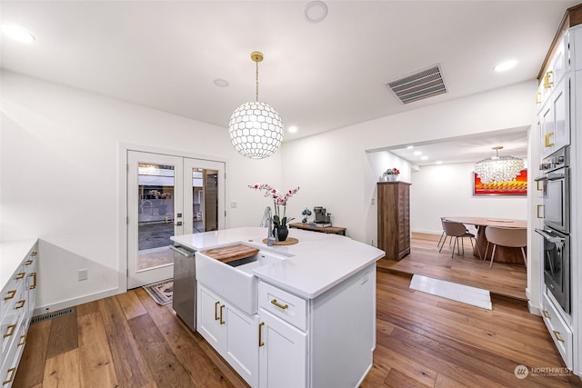 kitchen with a center island with sink, white cabinetry, and pendant lighting