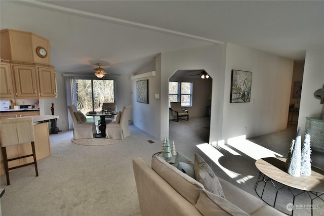 living room featuring visible vents, arched walkways, a ceiling fan, light colored carpet, and lofted ceiling