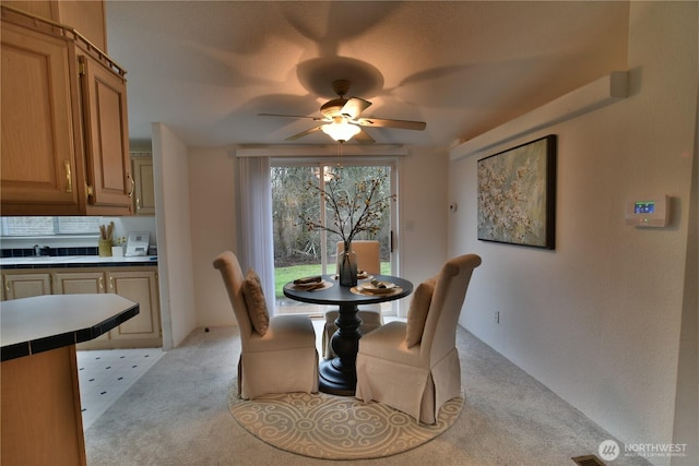 dining space featuring light carpet and a ceiling fan