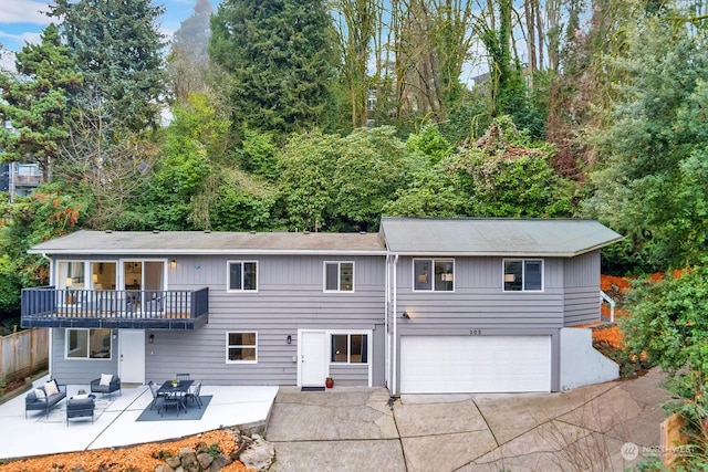 rear view of house with a balcony, a garage, an outdoor hangout area, and a patio area