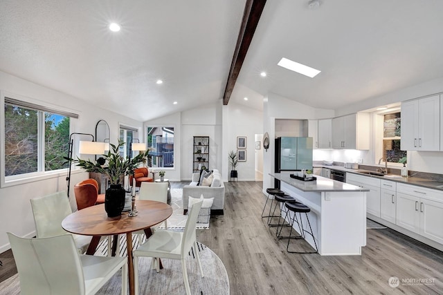 kitchen featuring a kitchen breakfast bar, stainless steel appliances, a center island, sink, and white cabinetry