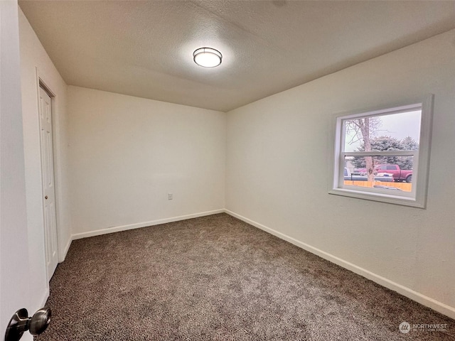 unfurnished room with a textured ceiling and dark colored carpet