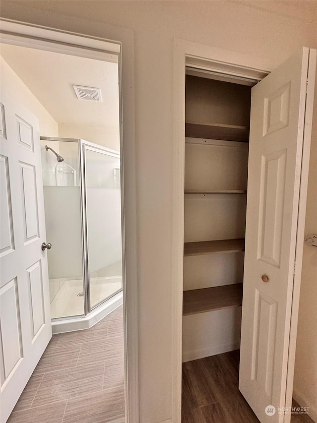 bathroom with hardwood / wood-style flooring and a shower with shower door