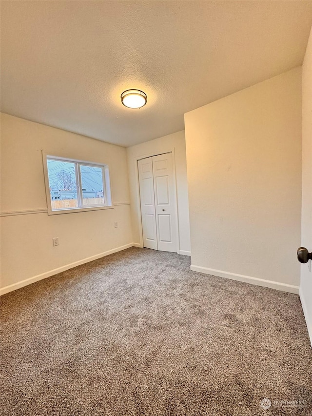 unfurnished bedroom featuring carpet, a textured ceiling, and a closet