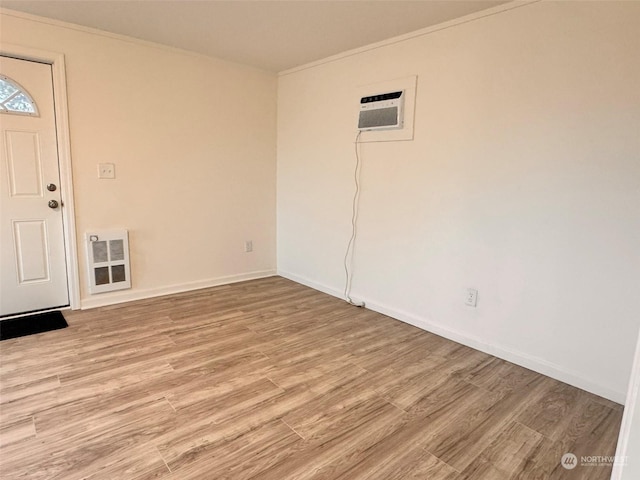 entryway featuring heating unit, light hardwood / wood-style floors, ornamental molding, and a wall mounted AC