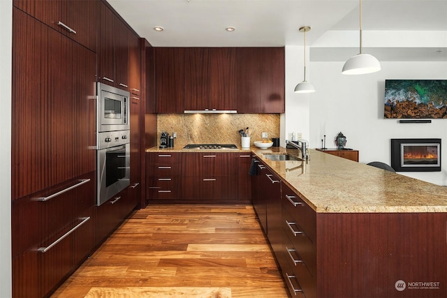 kitchen featuring sink, hanging light fixtures, light wood-type flooring, tasteful backsplash, and stainless steel appliances