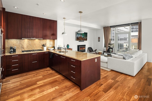 kitchen featuring sink, light hardwood / wood-style flooring, kitchen peninsula, pendant lighting, and decorative backsplash