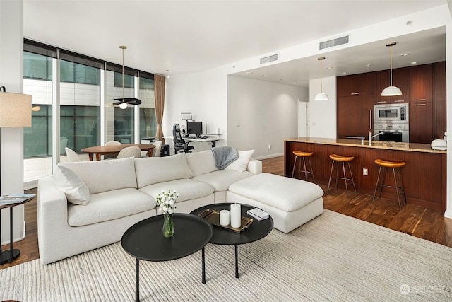 living room with a wealth of natural light, light hardwood / wood-style flooring, and ceiling fan