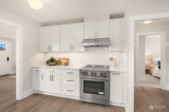 kitchen with hardwood / wood-style flooring, white cabinetry, backsplash, and stainless steel stove