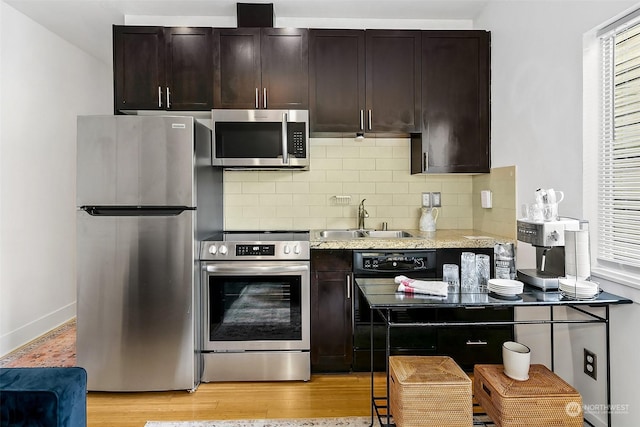 kitchen featuring sink, stainless steel appliances, tasteful backsplash, light hardwood / wood-style flooring, and dark brown cabinets