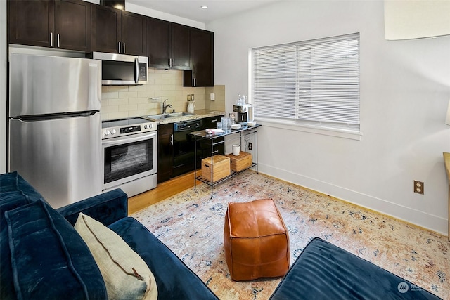 kitchen featuring decorative backsplash, dark brown cabinetry, stainless steel appliances, sink, and light hardwood / wood-style flooring