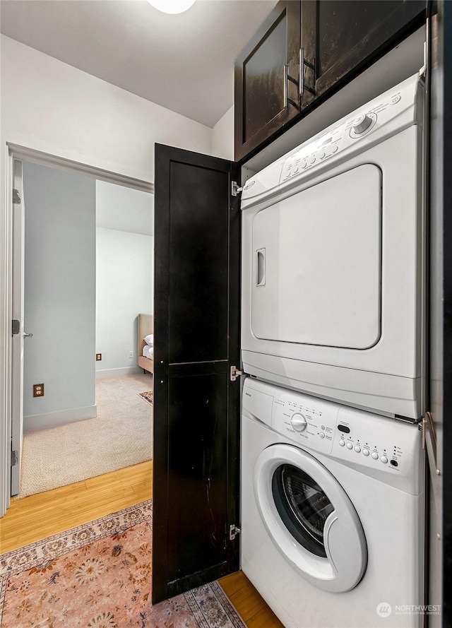 laundry area with stacked washing maching and dryer and hardwood / wood-style flooring