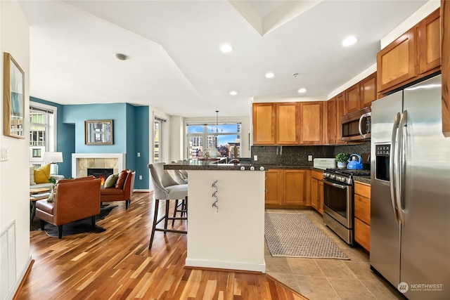 kitchen featuring a breakfast bar, plenty of natural light, appliances with stainless steel finishes, and light hardwood / wood-style flooring