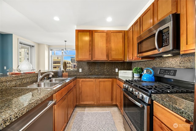 kitchen featuring appliances with stainless steel finishes, backsplash, sink, light tile patterned floors, and a chandelier