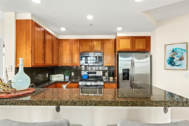 kitchen featuring kitchen peninsula, a kitchen breakfast bar, stainless steel appliances, and tasteful backsplash