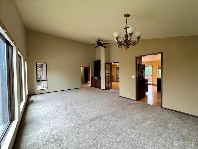 carpeted spare room with ceiling fan with notable chandelier, high vaulted ceiling, and a wealth of natural light