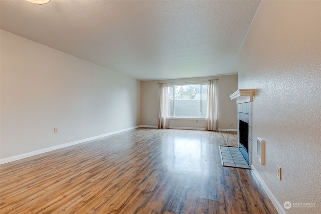 unfurnished living room with a fireplace, a textured ceiling, and hardwood / wood-style flooring