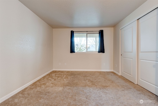 unfurnished bedroom with light carpet, a textured ceiling, and a closet