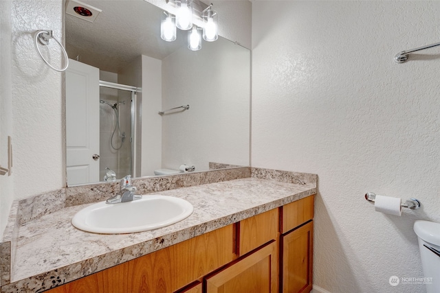 bathroom featuring walk in shower, vanity, a textured ceiling, and toilet