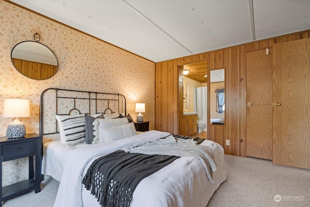 bedroom with lofted ceiling, light carpet, wooden walls, and connected bathroom