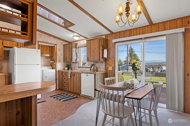 kitchen featuring white appliances, light carpet, decorative light fixtures, wooden walls, and a notable chandelier