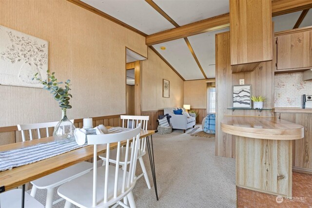 carpeted dining area with wooden walls and lofted ceiling