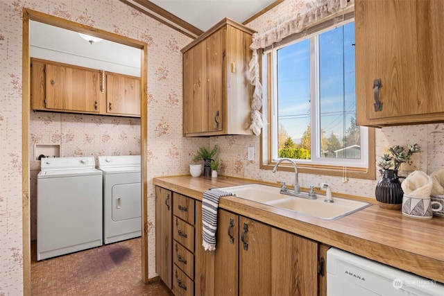 laundry area featuring crown molding, washer and clothes dryer, cabinets, and sink