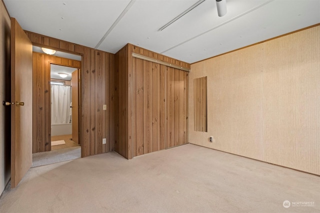 carpeted empty room featuring wood walls