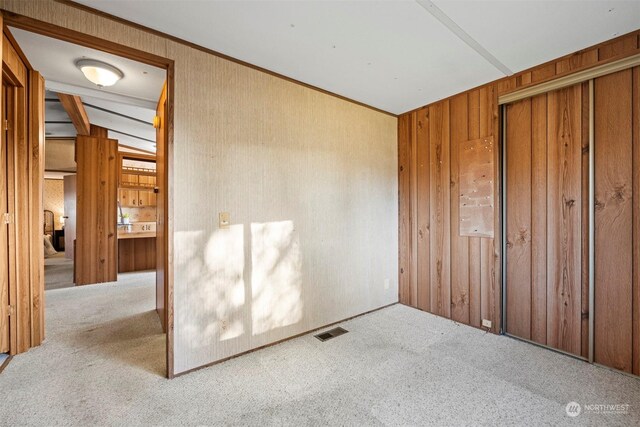 unfurnished bedroom featuring lofted ceiling with beams, light colored carpet, and a closet