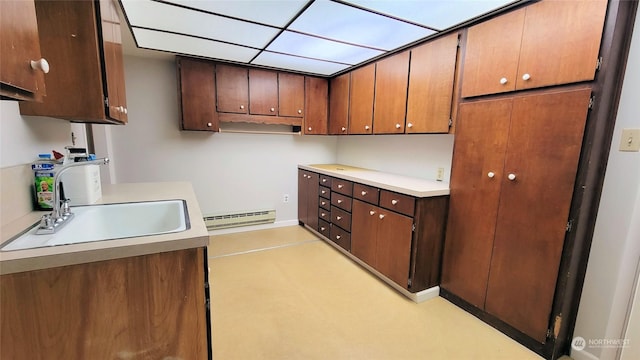 kitchen with light countertops, a baseboard heating unit, and a sink