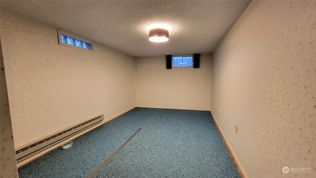 basement featuring carpet flooring, a textured ceiling, and a baseboard heating unit