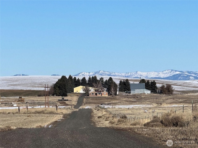 view of road with a rural view and a mountain view