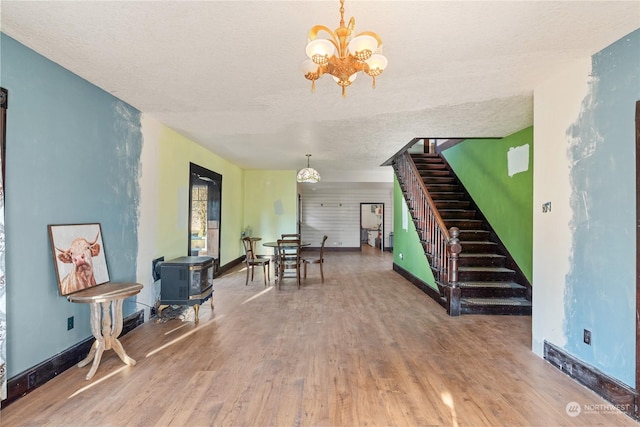 interior space with a wood stove, hardwood / wood-style floors, a textured ceiling, and an inviting chandelier