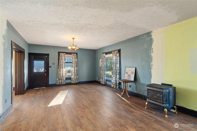 interior space featuring a wood stove, dark hardwood / wood-style flooring, a chandelier, and a textured ceiling