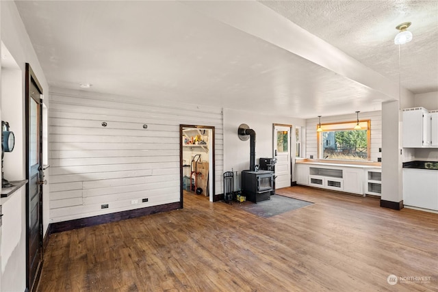 unfurnished living room with dark hardwood / wood-style flooring, a wood stove, and a textured ceiling