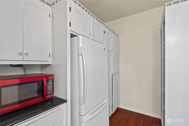 kitchen featuring dark hardwood / wood-style floors, white fridge, white cabinetry, and a textured ceiling